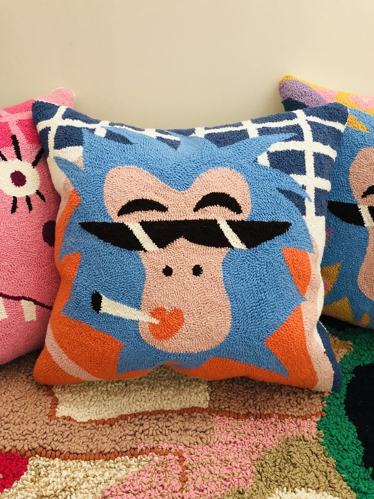 Trippy face Colorful Vibrant tufted cotton cushion cover with abstract design,
Colorful pillows with cartoonish designs on a textured surface.