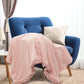 Blue armchair with a pink blanket and beige pillow in a cozy room.