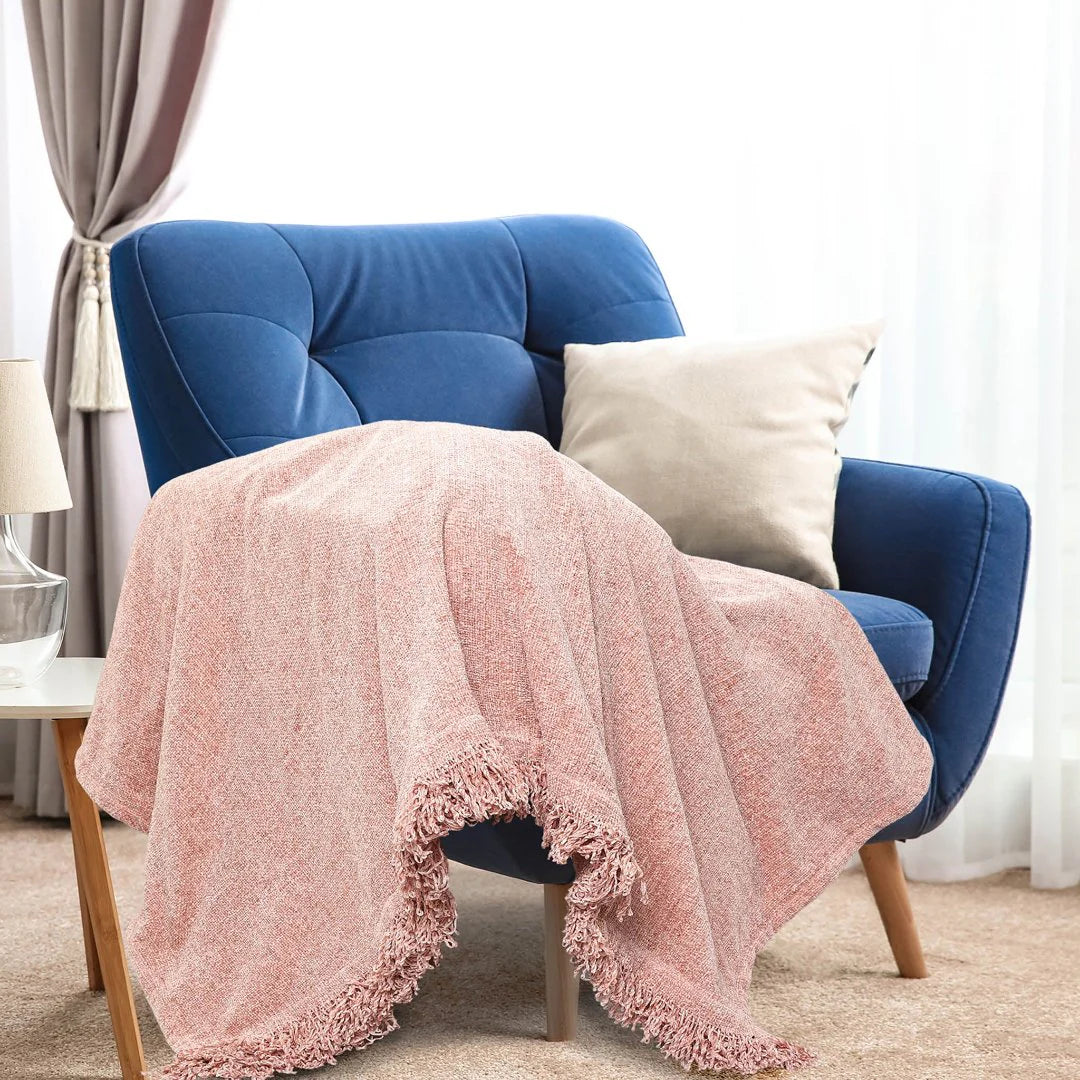 Blue armchair with a pink blanket and beige pillow in a cozy room.