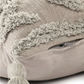 Beige pillow with textured surface and tassels on a light background