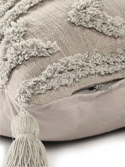 Beige pillow with textured surface and tassels on a light background