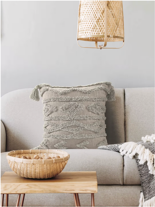 Gray textured pillow on a beige sofa with a wooden coffee table and woven lamp in a living room setting.